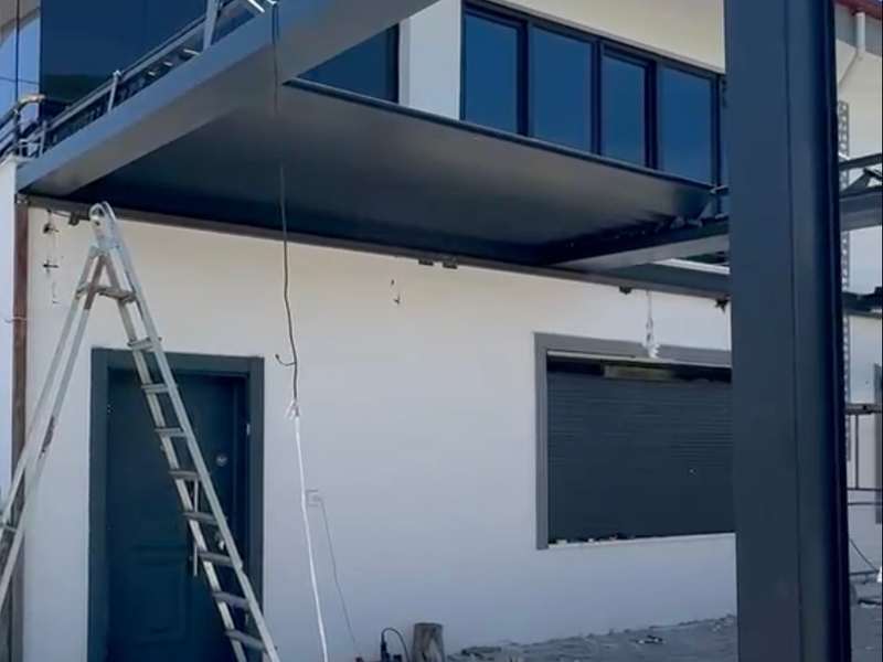 Montaj sahası: bina cephesine kurulan çelik taşıyıcı konstrüksiyon, arkasındaki pencerede kapalı konumda antrasit alüminyum panjur