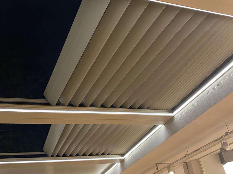 Toplanmış krem katlanır çatı panellerinin gece yakın planı; panel kıvrımları ve LED aydınlatma hattı belirgin