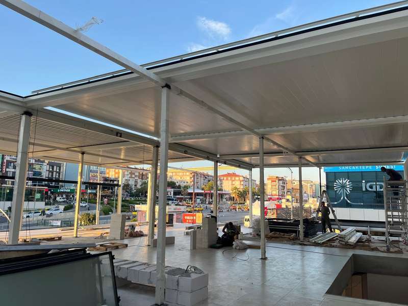 İstanbul Sancaktepe'de bir şube binasının önündeki geniş açıklıklı beyaz rolling roof sistemi; montaj devam ederken içeriden cadde görünümü