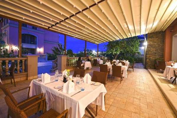 Akşam servisine hazırlanmış restoran terasında açılmış rolling roof çatı; LED aydınlatma ve beyaz örtülü masalar