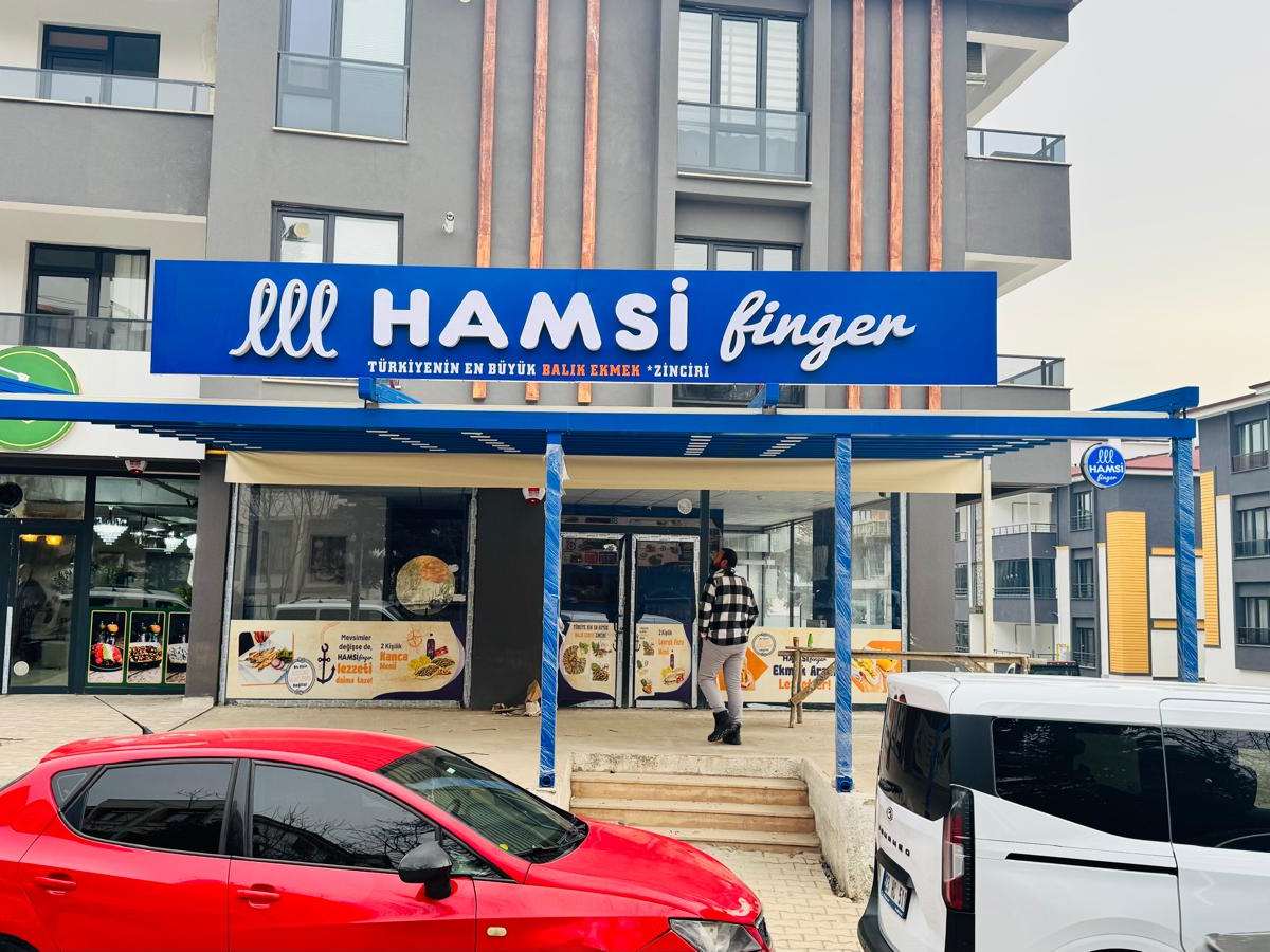Hamsi Finger restoranının cephesine kurulan mavi-beyaz alüminyum pergola; tabelanın altında dış oturma alanını örtüyor